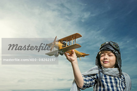Boy with wooden airplane outdoors