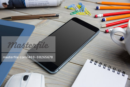 Smartphone next to the cup notepad tablet at the office