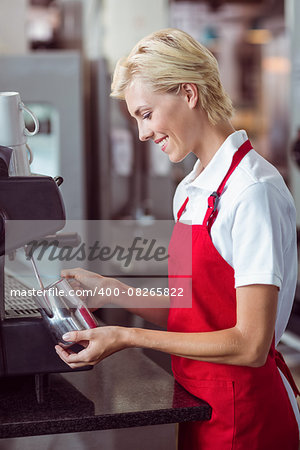 Pretty barista using the coffee machine at the cafe