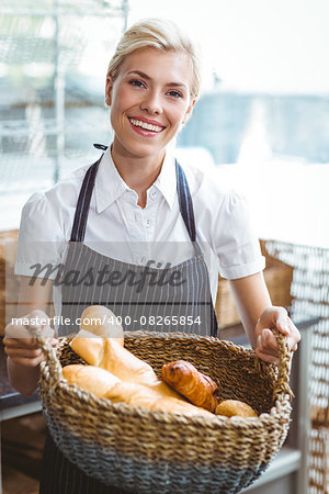 Pretty waitress carrying basket of bread at the baker