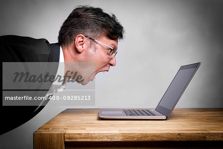 Man sitting at the table and screaming at his laptop