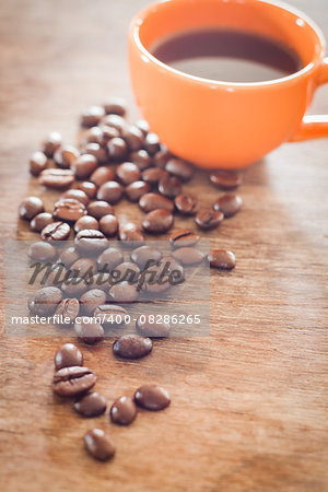 Coffee beans with coffee cup on wooden table, stock photo