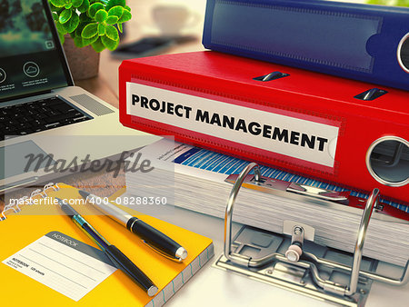 Red Office Folder with Inscription Project Management on Office Desktop with Office Supplies and Modern Laptop. Business Concept on Blurred Background. Toned Image.