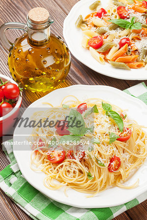Spaghetti and penne pasta with tomatoes and parsley on wooden table