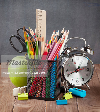 School and office supplies, alarm clock and apple on classroom table