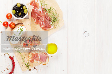 Bruschetta with cheese, tomatoes and prosciutto on cutting board. Top view with copy space