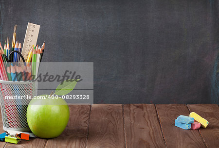 School and office supplies on classroom table in front of blackboard. View with copy space