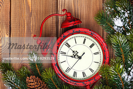 Christmas clock and snow fir tree over wooden background