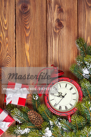 Christmas wooden background with clock, snow fir tree and gift boxes