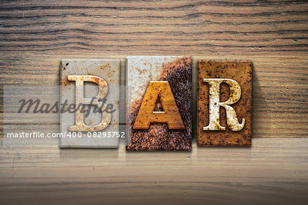 The word "BAR" written in rusty metal letterpress type sitting on a wooden ledge background.