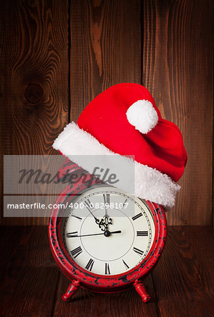 Christmas alarm clock with santa hat on wooden table