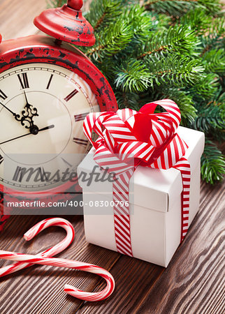 Christmas alarm clock, gift box and fir tree branch on wooden table