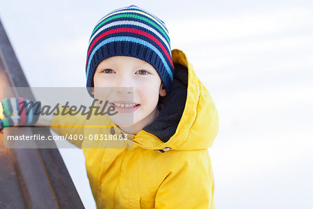 little boy enjoying cold winter weather and ice skating at outdoor rink