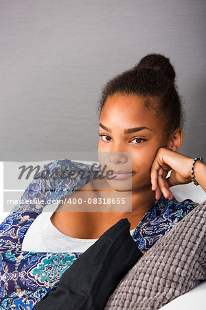 Teenage girl sitting in a couch looking into camera with a friendly smile