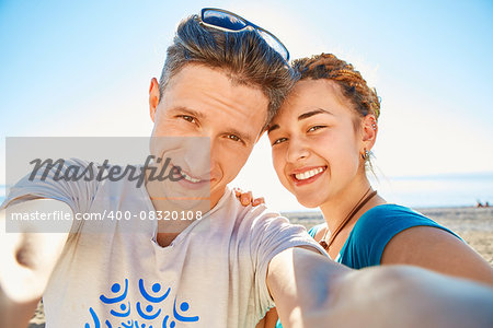 happy attractive man and woman looks into the camera on the sunny beach over the blue sky. Focus on the man