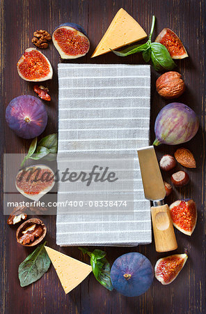 Grey linen napkin in a frame of fresh figs, nuts and herbs .