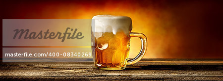 Light beer in glass mug on wooden table