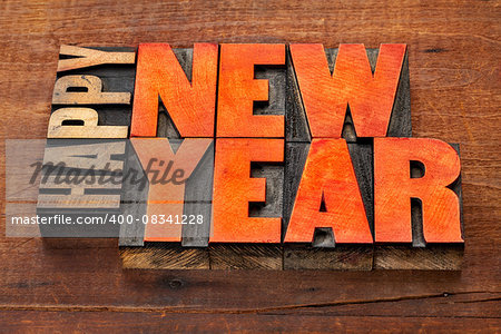 Happy New Year greeting card  - word abstract in vintage letterpress wood type blocks stained by red ink  on a grunge wooden background