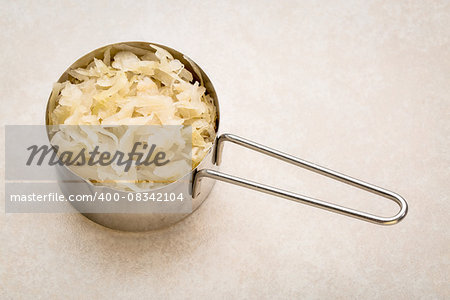 metal measuring scoop of sauerkraut against ceramic tile - healthy eating concept (probiotic food)