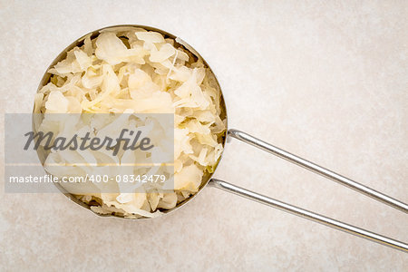 top view of metal measuring scoop of sauerkraut against ceramic tile - healthy eating concept (probiotic food)