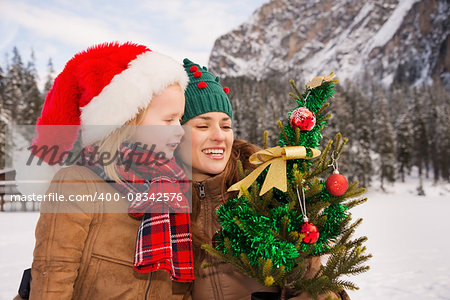 Winter outdoors on Christmas can be fairytale-maker for a children or even an adults. Portrait of happy mother and child looking on Christmas tree in the front of mountains