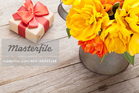 Colorful tulips bouquet and gift box over wooden table background