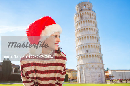 Young, itching from energy and searching for excitement. I'm going to Christmas trip to Italy. It is a no-brainer. Happy woman in Santa hat looking on something in front of Leaning Tour of Pisa.