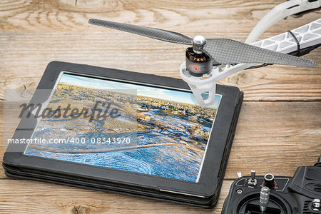 drone aerial photography concept - reviewing aerial picture of Colorado foothills near Fort Collins on a digital tablet with a drone rotor and radio control transmitter, winter scenery