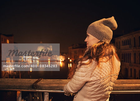 Tune in for charming winter time in Venice, Italy. Seen from behind, young woman standing on a bridge and looking on Grand canal