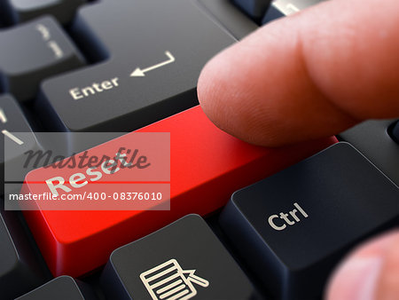 Finger Presses Red Button  Reset on Black Keyboard Background. Closeup View. Selective Focus.