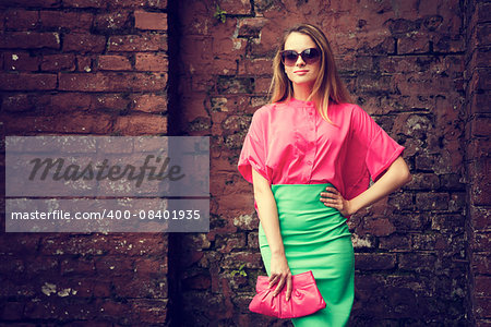 Beautiful Fashionable Woman Standing at the Old Brick Wall Background. Urban Fashion Concept. Toned Photo with Copy Space.
