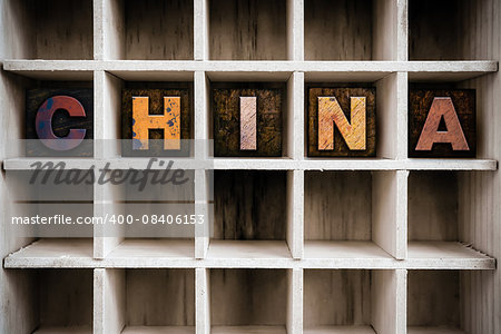 The word "CHINA" written in vintage ink stained wooden letterpress type in a partitioned printer's drawer.