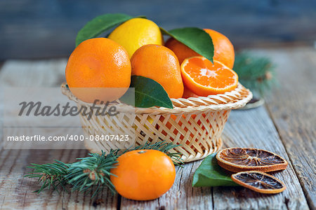 Tangerines and lemons with leaves in a wicker basket.