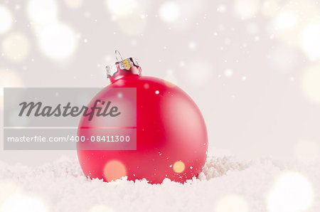 red decorative christmas ball on snow against grey festive background