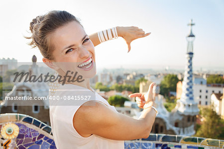 Refreshing promenade in unique Park Guell style in Barcelona, Spain. Smiling young woman tourist framing with hands in Park Guell, Barcelona, Spain