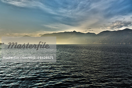 sunset over the lake major with the mists of the horizon and mountains in the background on a winter afternoon, Luino - Lombardy, Italy