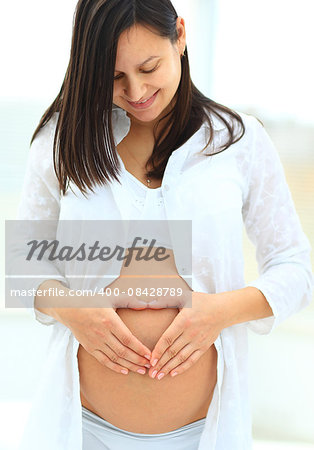 woman holds her baby bump and looking up