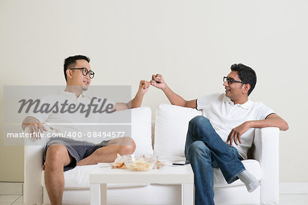 Friends sitting on sofa and giving hand promise at home. Multiracial people friendship.