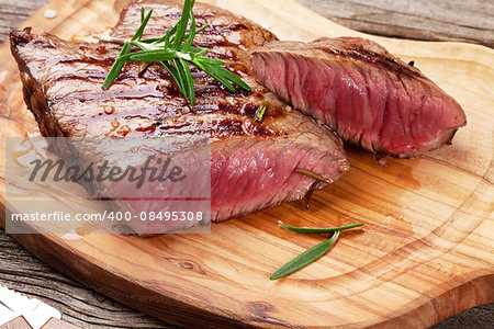 Grilled beef steak with rosemary, salt and pepper on wooden board