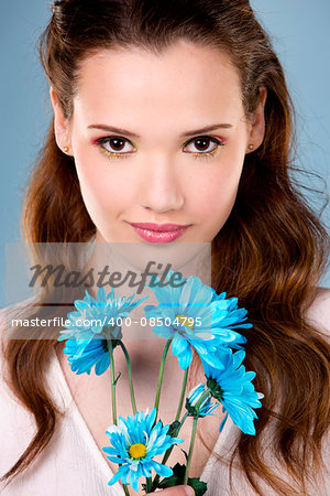 young cuacasian woman holding flower on blue background