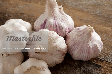 Group of fresh garlic bulbs for use as a pungent aromatic seasoning in cookery lying on a wooden table