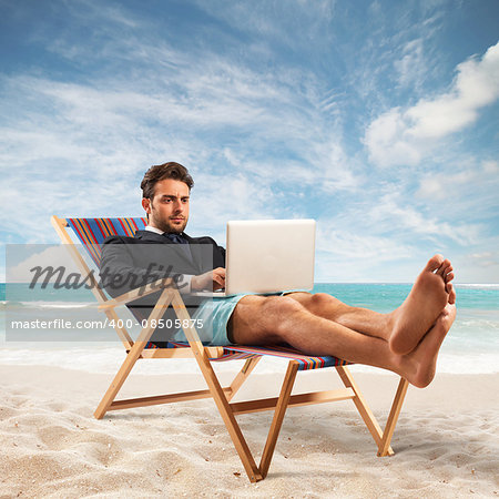 Businessman works with computer at the beach