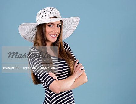 young woman wearing dress and white hat on blue background