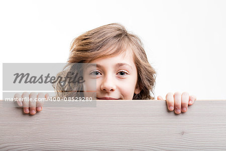 girl looks from behind a copy space represented by a wooden board