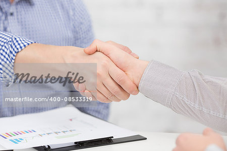 Two business people shaking hands indoors. Man and woman are business partners, who agreed to sign contract or agreement.