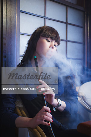 Concept: leisure lifestyle. Beautiful young woman with hookah in a bar restaurant