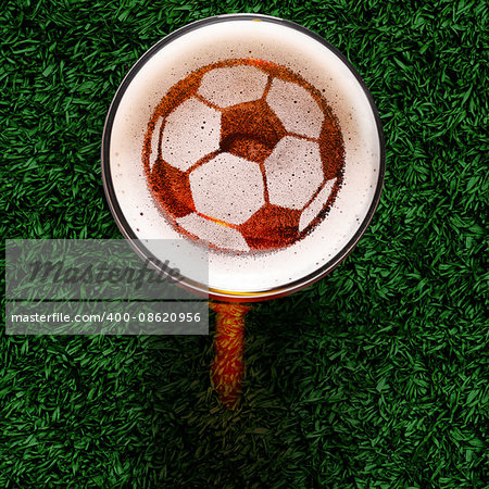 soccer or football ball symbol on foam of fresh lager beer glass on grass, view from above