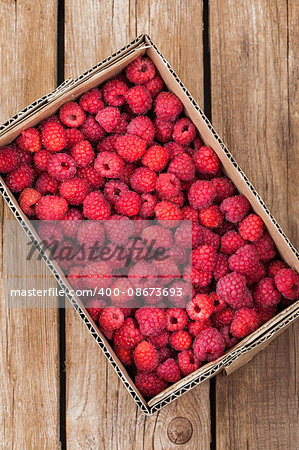 Fresh organic ripe raspberry in box on wooden table