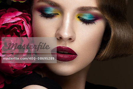 Beautiful girl with colorful make-up, flowers, retro hairstyle The beauty of the face. Photos shot in studio