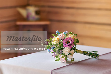 Beautiful wedding bouquet made of polymer clay, lying on white tablecloth.